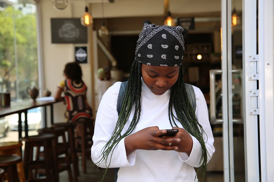 woman at cafe looking down at mobile phone in her hand