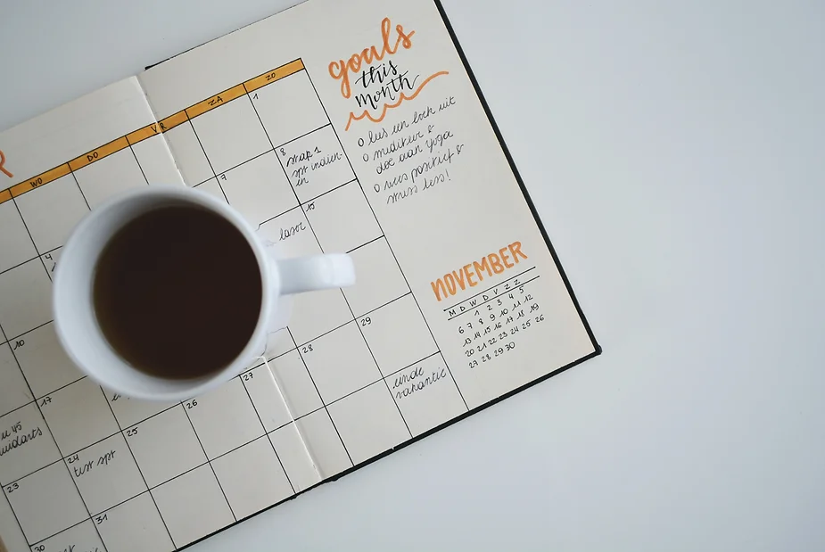 flatlay photo of open planner with coffee mug on top
