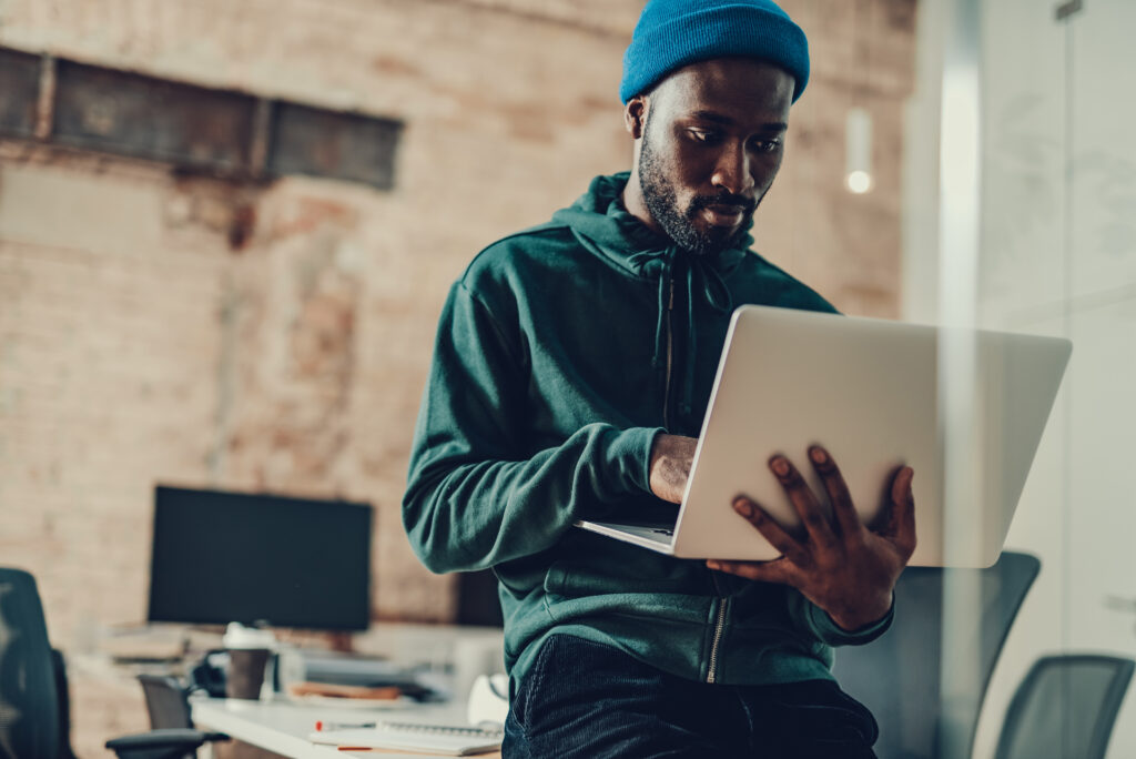 Calm man in casual clothes sitting alone in the office and using modern laptop to look for short term loans