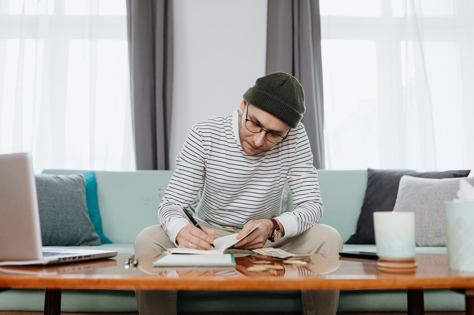 man in white and black stripe long sleeve shirt sitting on blue couch doing budgeting