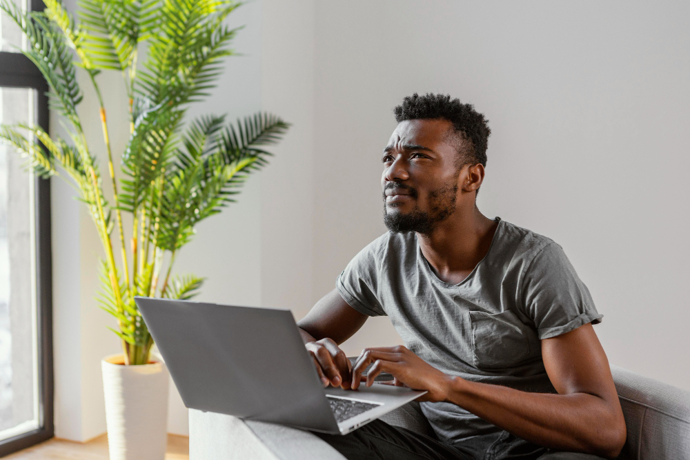man on his laptop sitting next to a tree